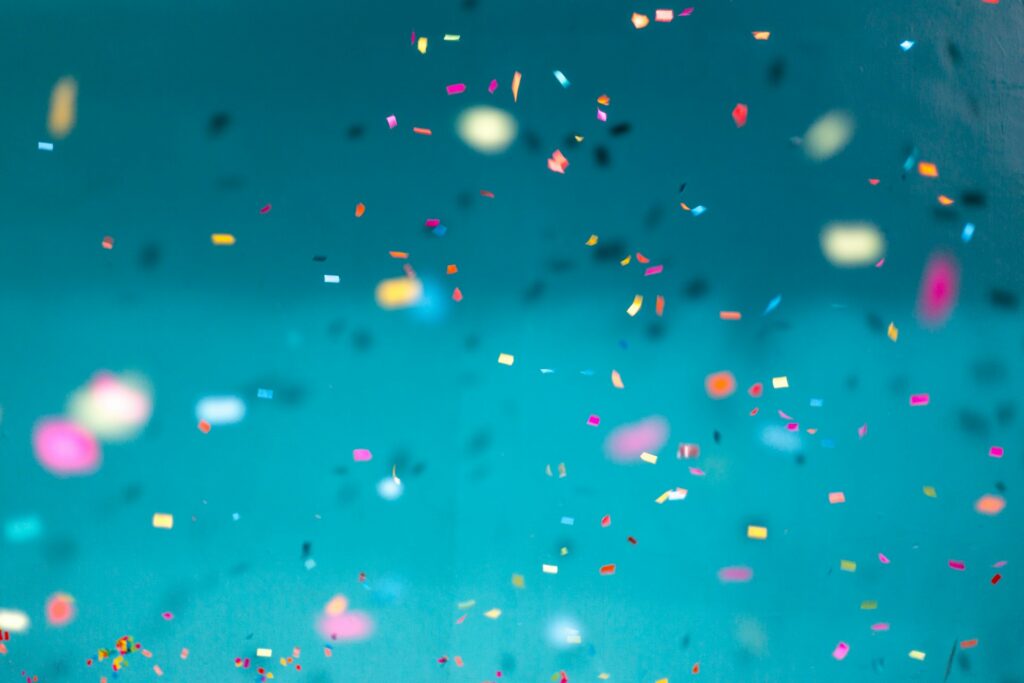 Colourful falling confetti on a teal background